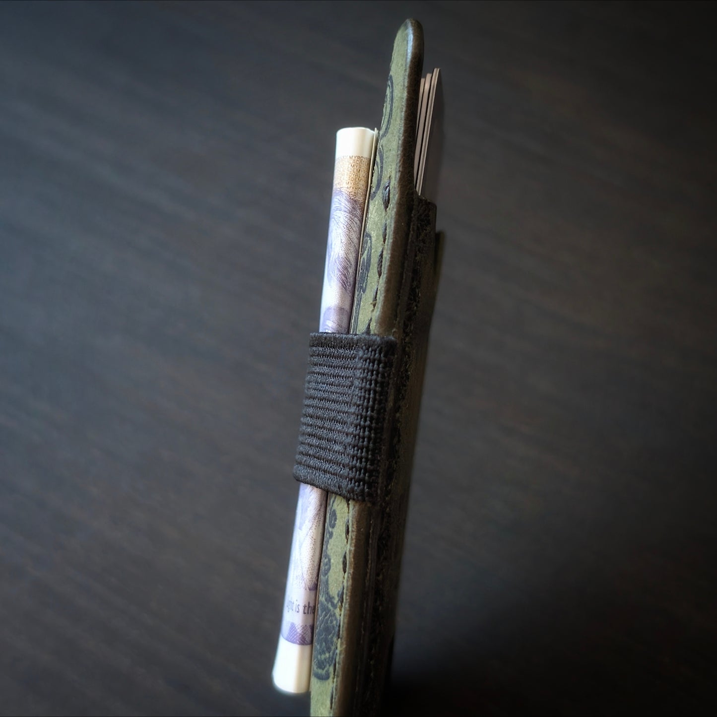 A tight closeup highlighting the ruggedly sleek profile and glass-slick, hand-burnished edges of The Melee in Olive.