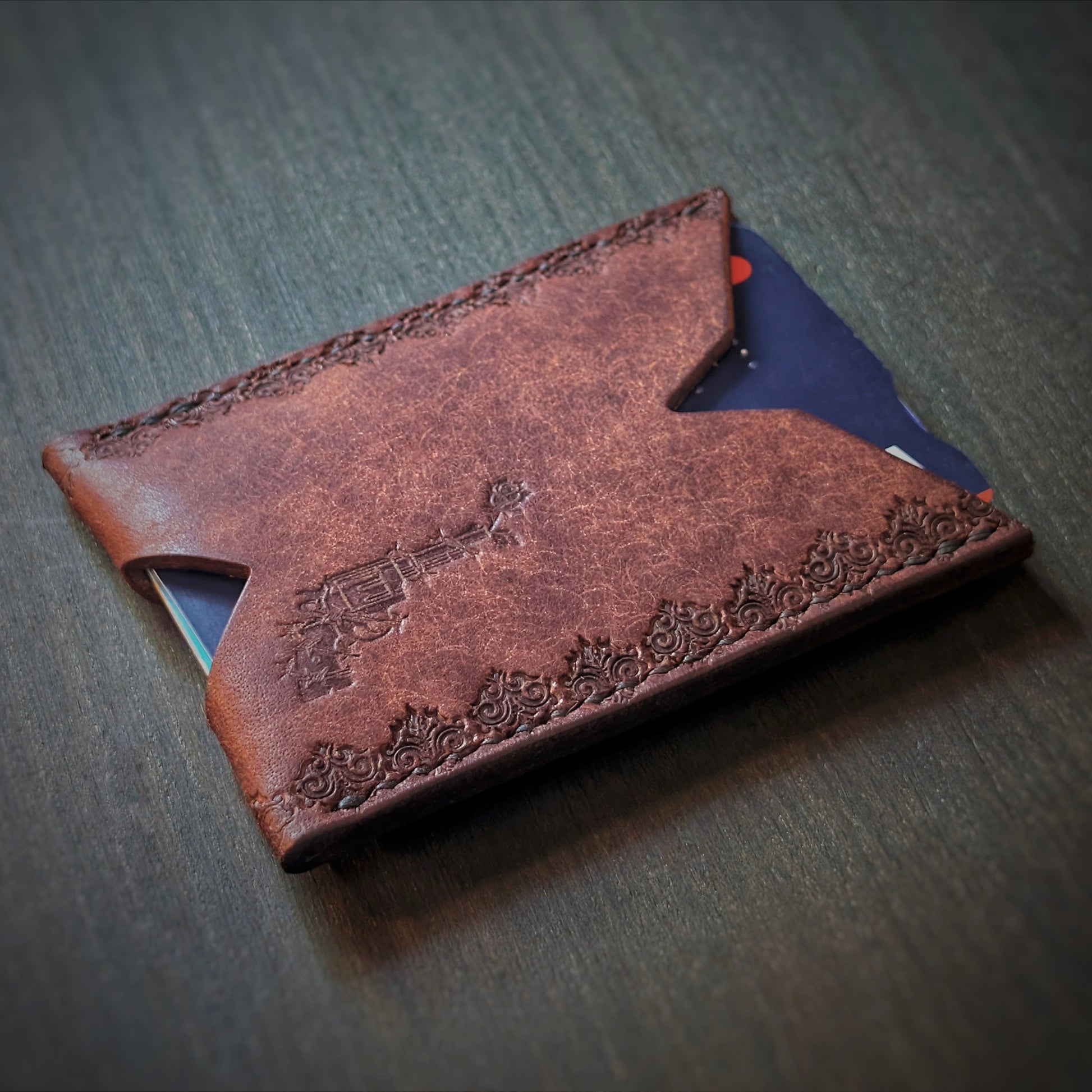 Angled view of El Rey Leather's Deadbeat minimalist wallet in tobacco with cards, showing the logo.