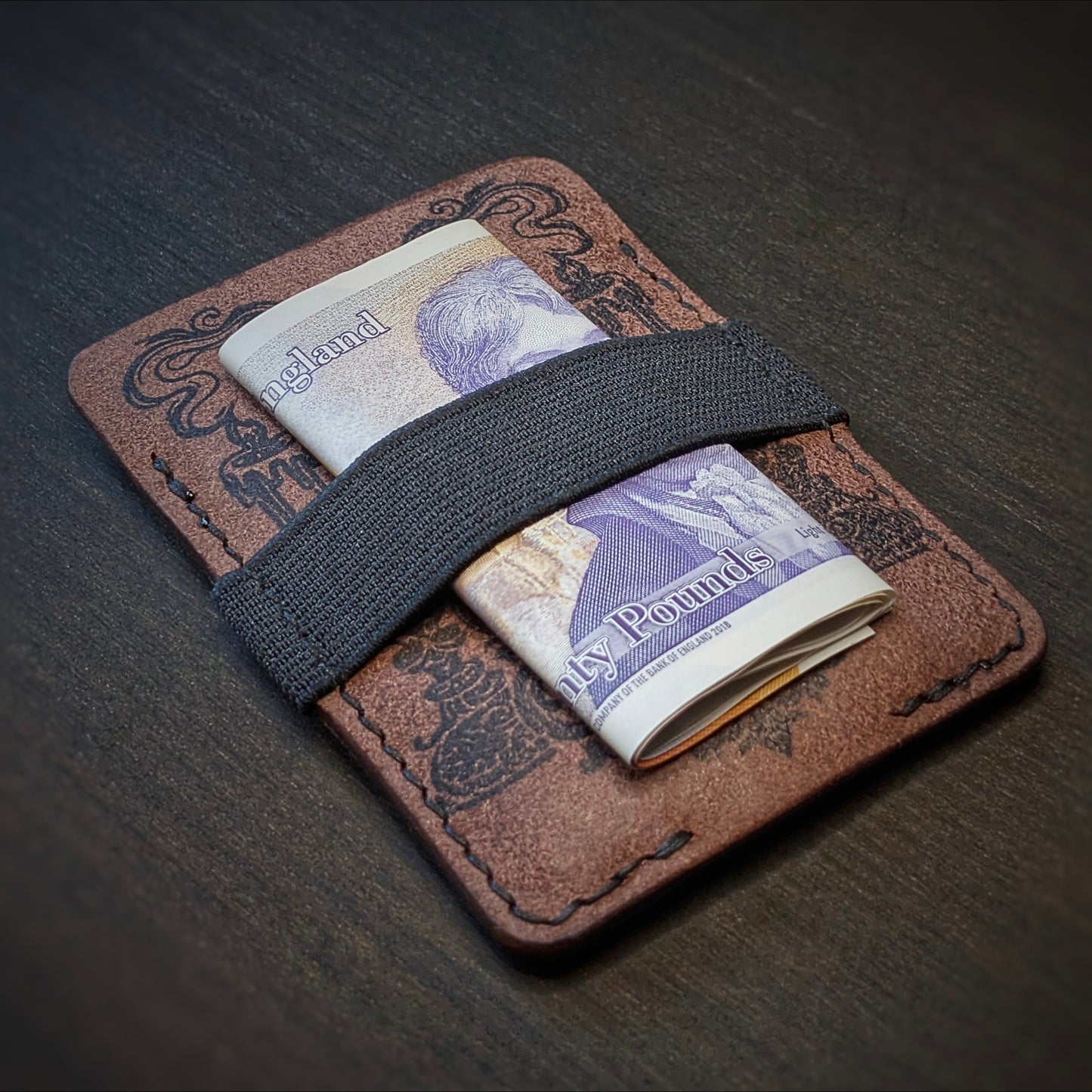Tobacco Melee EDC wallet by El Rey Leather holding a folded UK banknote under a black elastic strap.