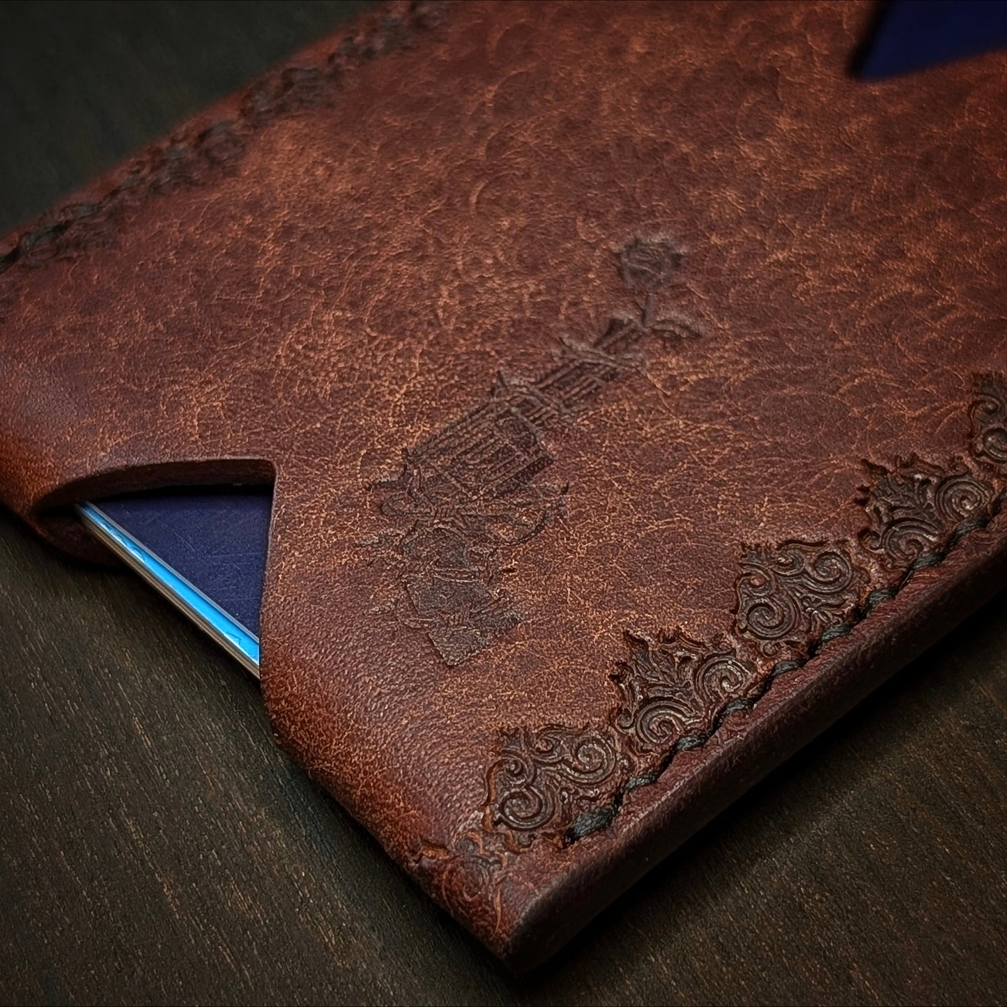 Macro shot of the saddle stitching and gothic border stamp on The Deadbeat tobacco leather wallet.