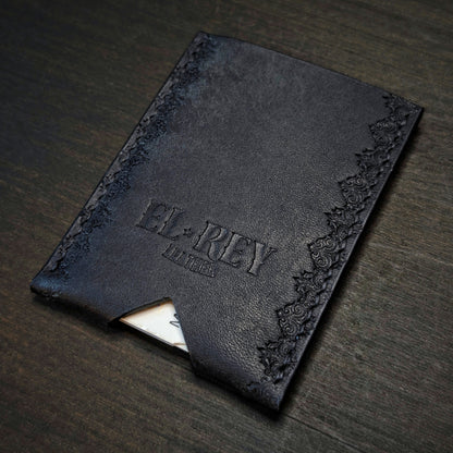 Rear angled view of El Rey Leather's Deadbeat minimalist wallet in black with cards, showing the hand-stamped border.