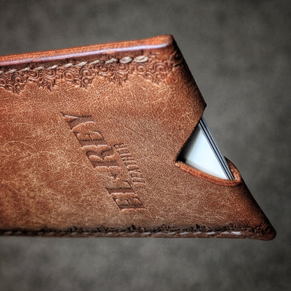 Macro shot of the saddle stitching and gothic border stamp on The Deadbeat cognac leather wallet.