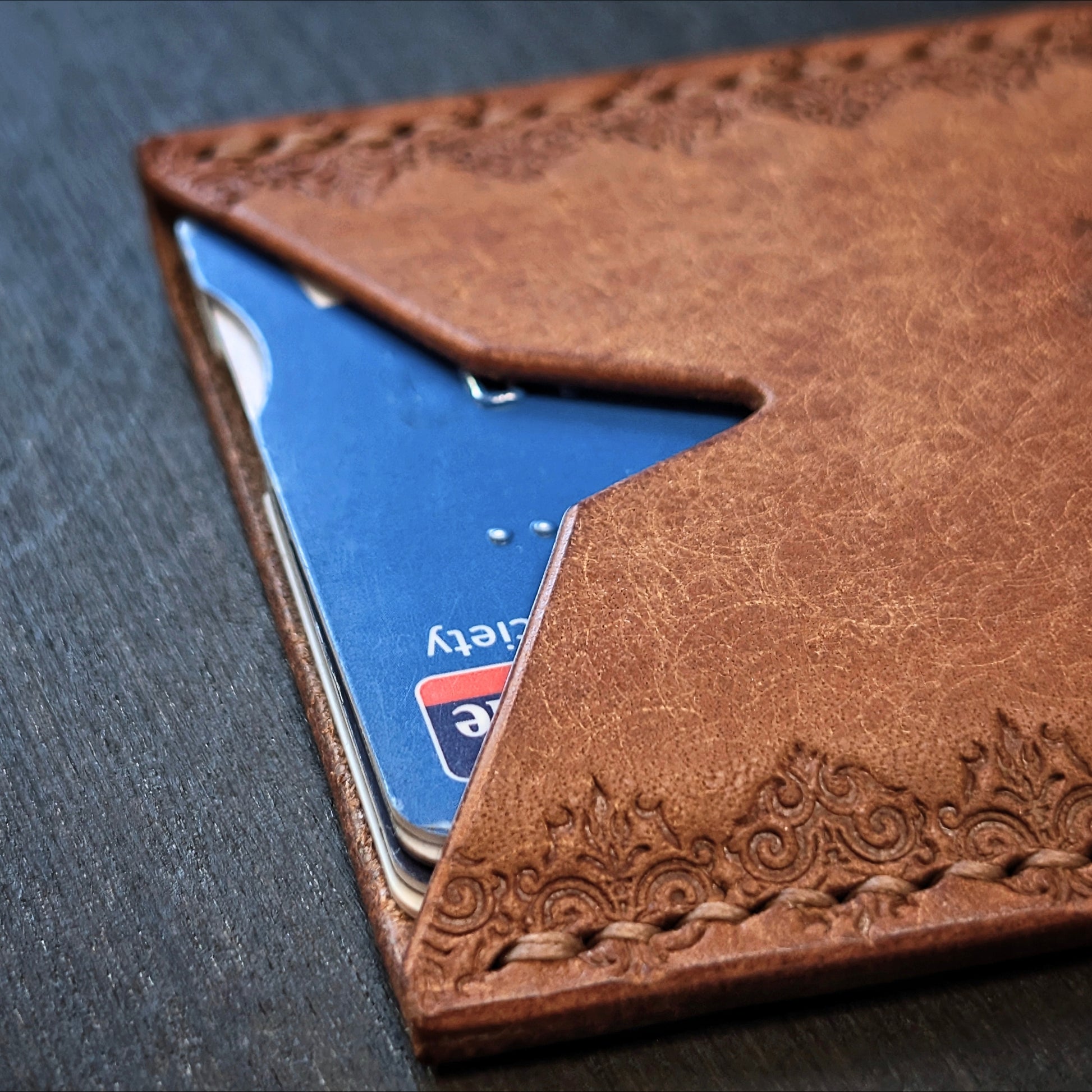 Macro shot of burnished edges and slim profile pocket design on The Deadbeat cognac leather wallet.
