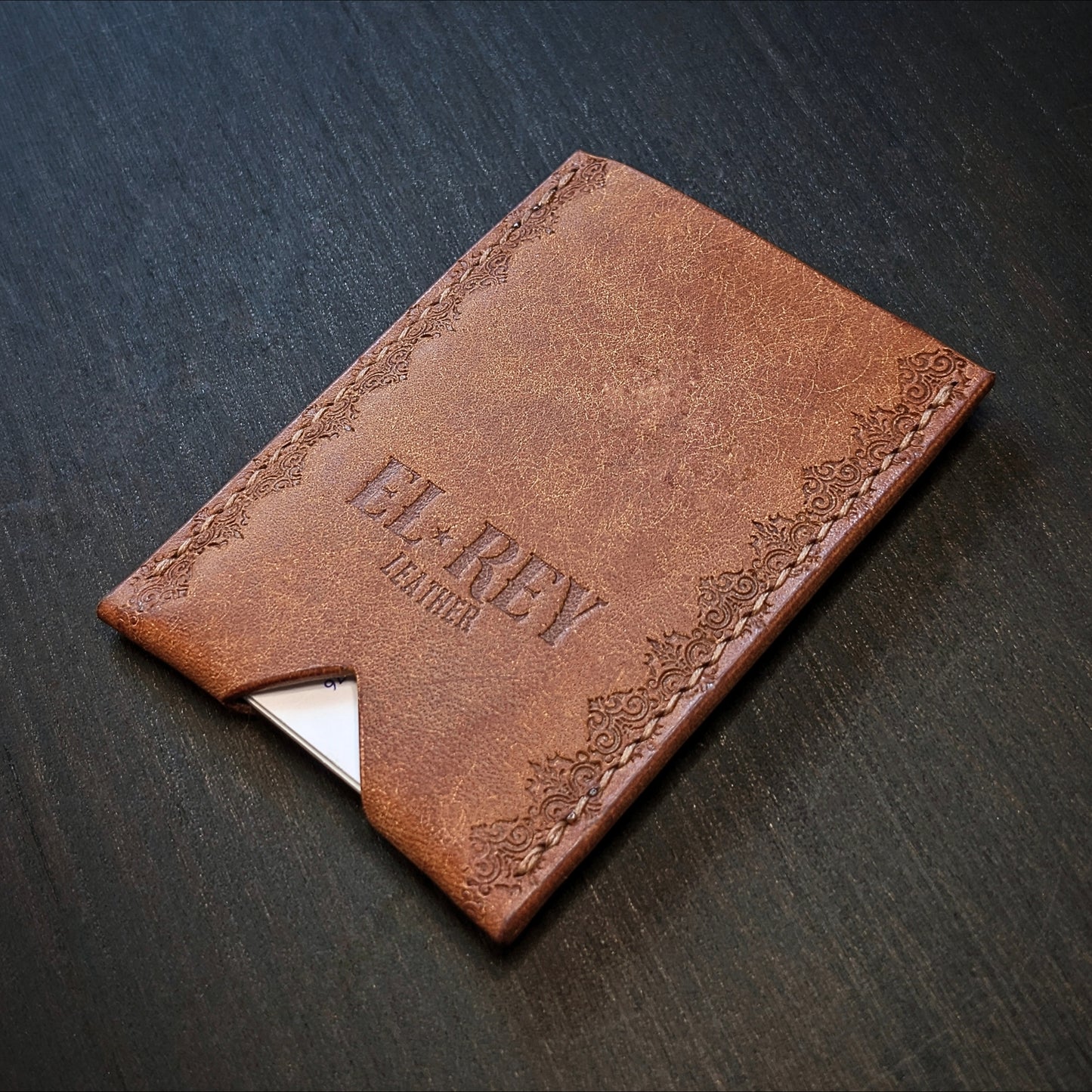 Rear angled view of El Rey Leather's Deadbeat minimalist wallet in cognac with cards, showing the hand-stamped border.