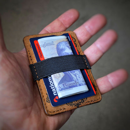 An open hand holding the El Rey Leather Melee EDC wallet in Cognac to demonstrate the woven elastic strap.