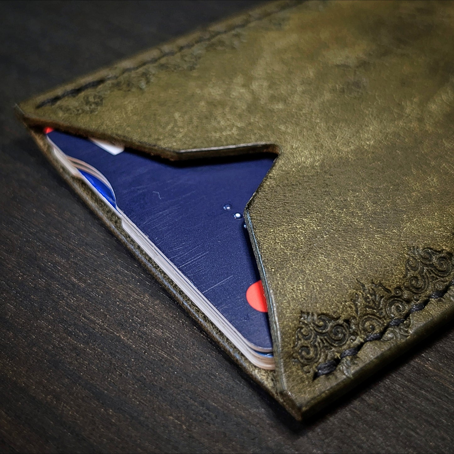 El Rey Leather Deadbeat minimalist leather wallet in olive holding bank cards with detailed hand-stamping.