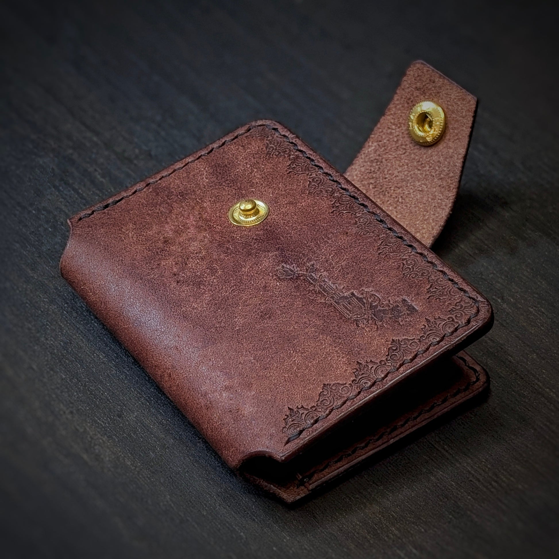 Angled view of El Rey Leather's Lowlife minimalist wallet in tobacco, showing the strap and brass snap button.