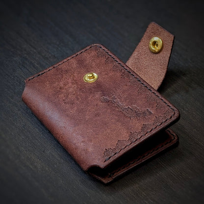 Angled view of El Rey Leather's Lowlife minimalist wallet in tobacco, showing the strap and brass snap button.