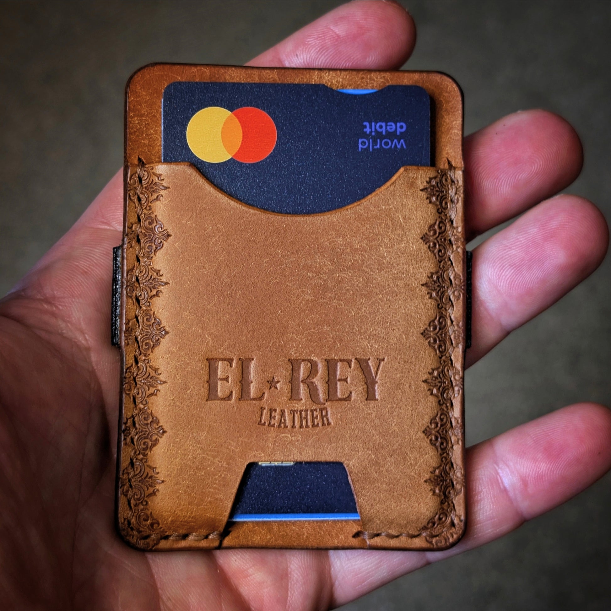 An open hand holding the El Rey Leather Melee minimalist wallet in Cognac to demonstrate its slim size.