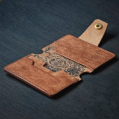 Angled flat lay view of El Rey Leather's Lowlife  minimalist wallet in cognac, showing the sugar skull ink design.