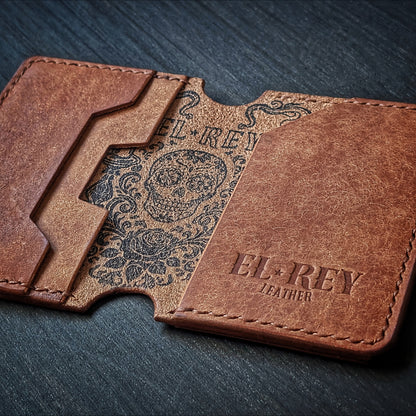 El Rey Leather Lowlife in cognac leather, featuring an inked sugar skull design and minimalist card slots.