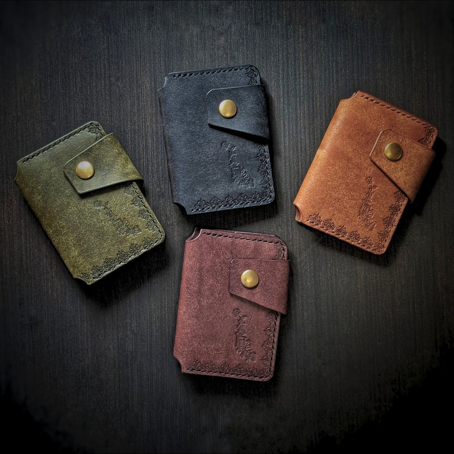 A moody overhead shot of four handcrafted El Rey Leather minimalist wallets in a range of colors.