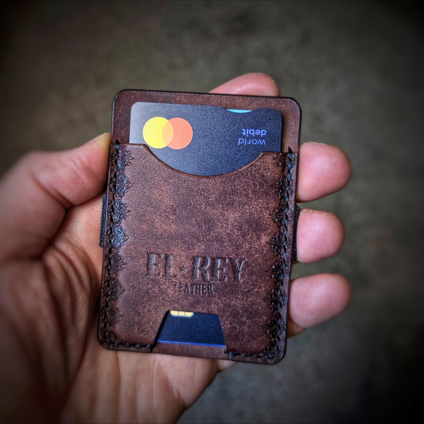 An open hand holding the El Rey Leather Melee minimalist wallet in Tobacco to demonstrate its slim size.