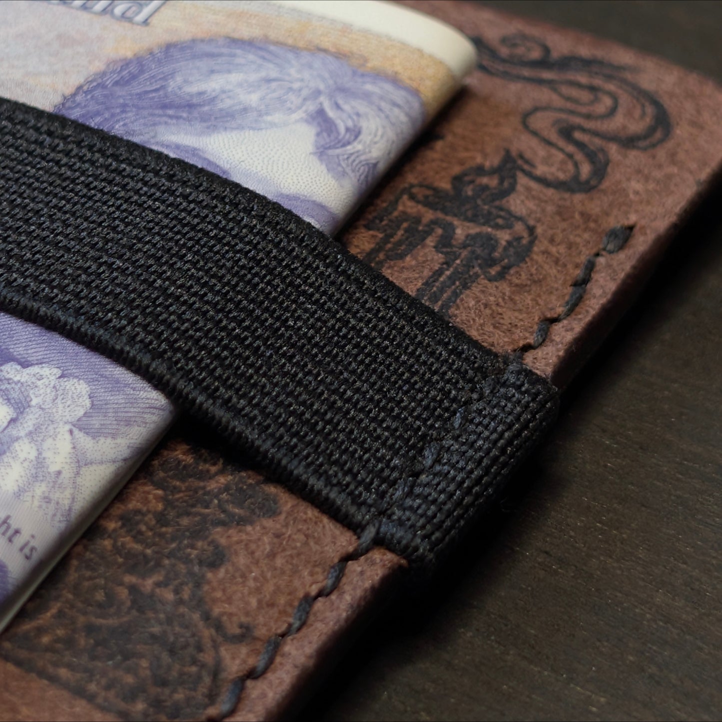 Detailed closeup of hand-sewn saddle stitching  and ink design on El Rey Leather's Melee wallet in Tobcco.